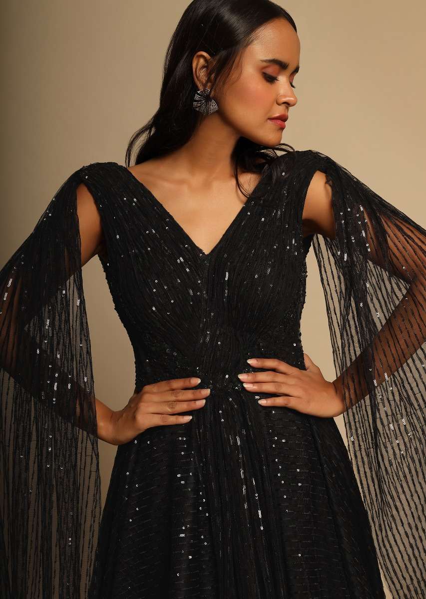 Black Gown In Sequins Embellished Net With Ruching In The Front, Sheer Sides And Net Cape On Each Shoulder