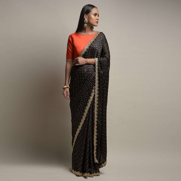 Black Saree In Satin Blend With Bandhani Print And Mirror Work Paired With Contrasting Coral Stitched Blouse