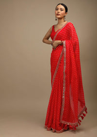 Coral Red Saree In Organza With Bandhani Buttis And Gotta Patti Embroidered Floral Motifs On The Border