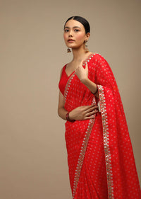 Coral Red Saree In Organza With Bandhani Buttis And Gotta Patti Embroidered Floral Motifs On The Border