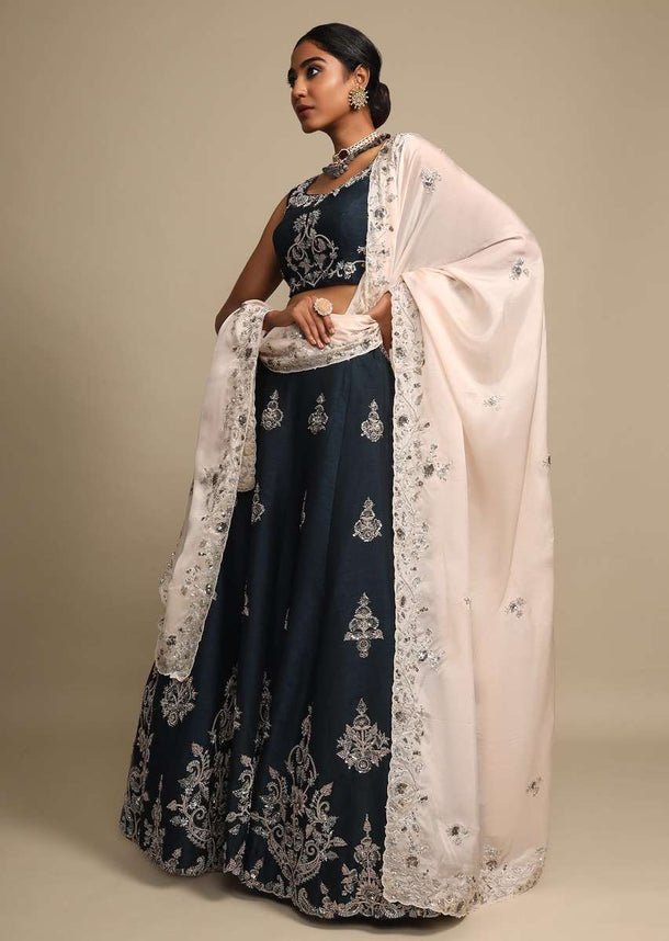 Midnight Teal Lehenga In Raw Silk With Zardozi Embroidered Floral Design On The Hem And Buttis Online - Kalki Fashion