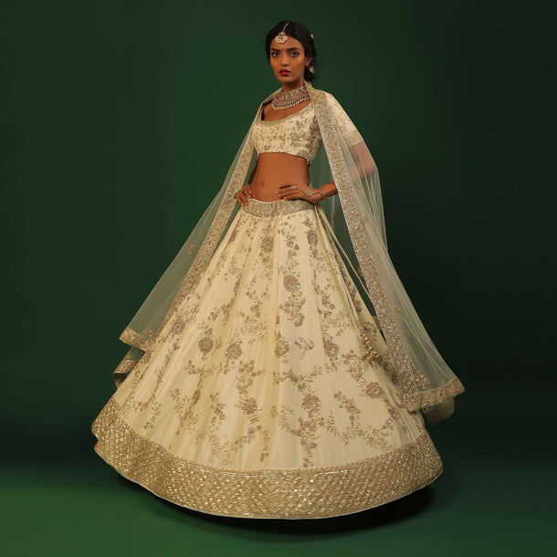 Off White Lehenga Choli In Raw Silk With Golden Cut Dana And Sequins Embroidered Floral Kalis And Geometric Border