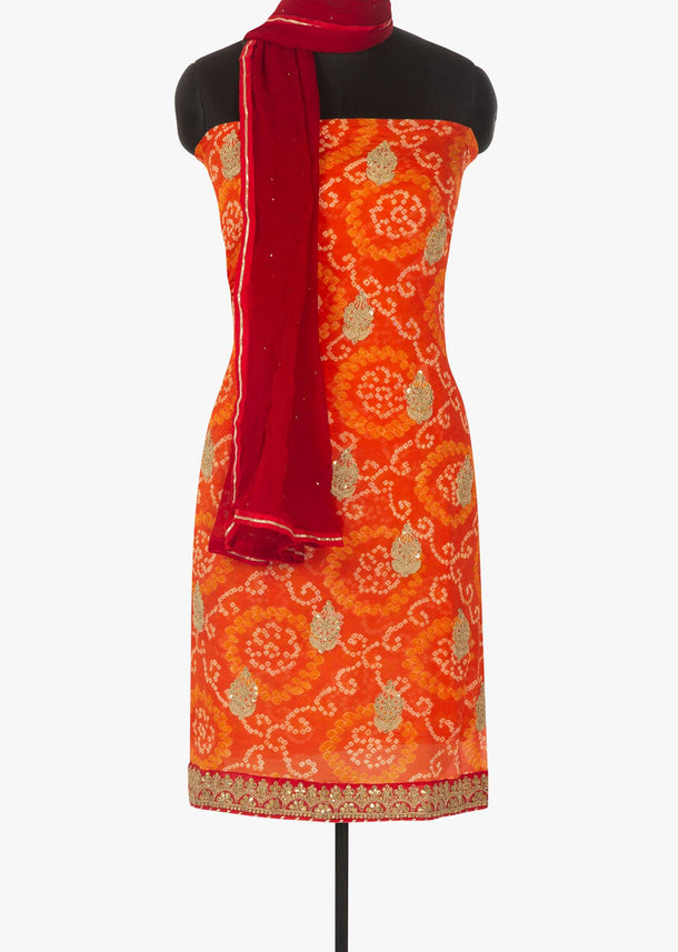 Orange unstitched suit in bandhani georgette with embroidered hem line only on Kalki